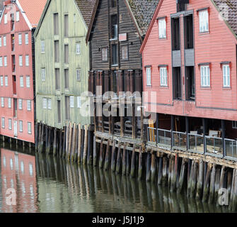 Antichi magazzini di legno in piedi su pali di legno sulle rive del fiume Nidelva. Trondheim, Sør-Trøndelag, Norvegia. Foto Stock