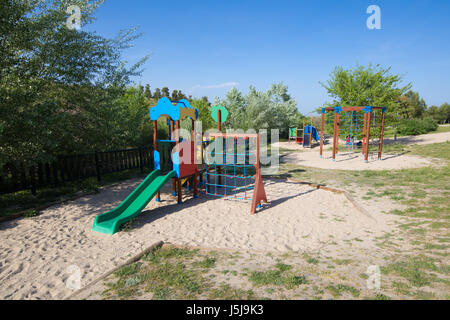 Plastica due insiemi di oscillazione sulla terra la massa di sabbia nel parco giochi con scivolo nel parco pubblico Stazione di depurazione di Valdebebas nella città di Madrid, Spagna Europa Foto Stock