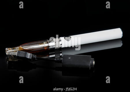 Sigaretta elettronica con caricatore su uno sfondo nero. Foto Stock