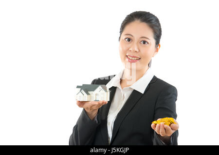 Donna asiatica azienda casa di proprietà e. che mostra il modello della casa e la moneta in oro su sfondo bianco. professionale e concetto di lavoro. Foto Stock