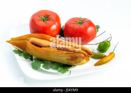 Tamales, Messicana piatto fatto con pasta di mais, pollo e peperoncino, avvolto con una foglia di mais isolato su bianco Foto Stock