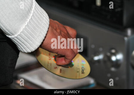 Dito mano ascoltare musica disco celebrazione di partito maglione tenere servire afferrare CD Foto Stock