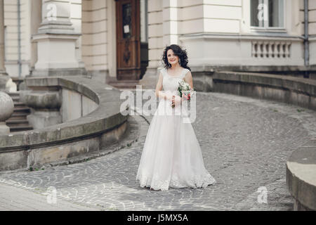 Sposa sorge nel cortile e sullo sfondo di una grande casa vecchia Foto Stock