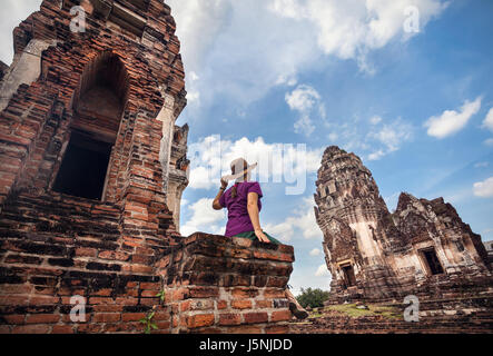 Donna in hat guardando antichi rovinato Tempio della città di Lopburi, Thailandia Foto Stock