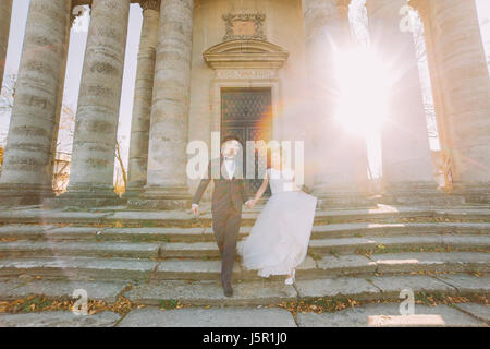 Gli sposi sono andando giù per le scale del palazzo antico durante il tramonto. Foto Stock