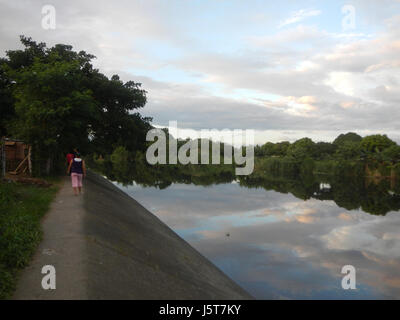 Questa immagine cattura la splendida vista del tramonto sul Ponte sul fiume Bocaue lungo la MacArthur Highway a Bocaue, Bulacan. La scena evidenzia la bellezza naturale del fiume e i colori vivaci del cielo al tramonto. Foto Stock