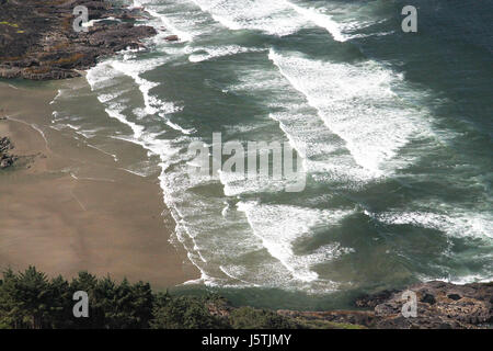 Questa fotografia mostra gli aspri e suggestivi paesaggi della costa dell'Oregon, caratterizzati dalle sue scogliere costiere, dalle onde e dai lussureggianti dintorni verdi. La costa offre vedute pittoresche ed è conosciuta per la sua bellezza naturale incontaminata. Foto Stock