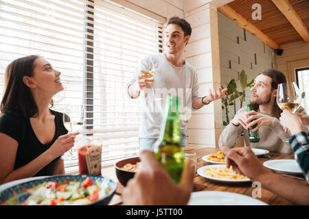 Un gruppo di giovani felici hanno bere e celebrare a tavola in casa Foto Stock