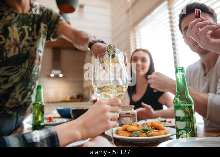 Gruppo di persone versando il vino nel bicchiere e a cena con gli amici a casa Foto Stock