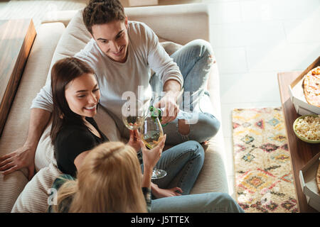 Vista dall'alto di felice giovani amici tintinnio dando i toast e bicchieri tintinnanti sul divano di casa Foto Stock