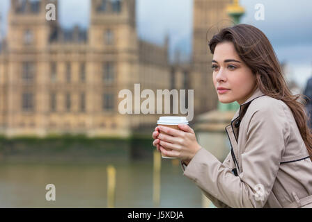 Bella triste e depresso o riflessivo giovane donna in Londra il Westminster Bridge sul fiume Tamigi a bere caffè asporto dal Big Ben Foto Stock