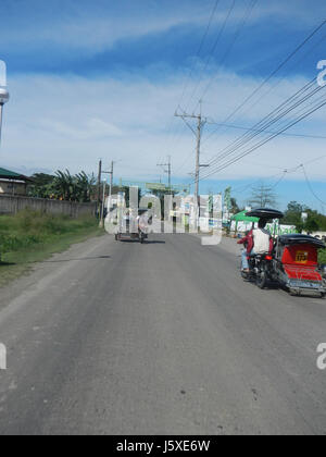 Questa immagine raffigura una vista della Cappella e della strada municipale a Manggahan, Santa Cruz, Santa Maria, Bulacan, Filippine. La scena cattura l'architettura locale e le infrastrutture tipiche di questa regione, offrendo informazioni sullo sviluppo urbano di Bulacan. Foto Stock