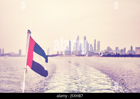 Vintage stilizzata Bandiera degli Emirati Arabi Uniti con skyline di Dubai in distanza di messa a fuoco selettiva. Foto Stock