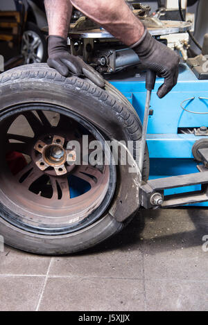 Uomo in auto le leve di riparazione di un pneumatico usato del cerchio Foto Stock