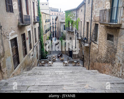 Guardando in giù per le scale di Pujada de Sant Domènec a tavoli e sedie per pranzare al fresco nella città di Girona, Spagna. Foto Stock