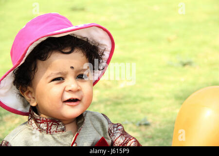 Piccola e dolce bambino indossando cappello rosa, cercando e sorridente Foto Stock