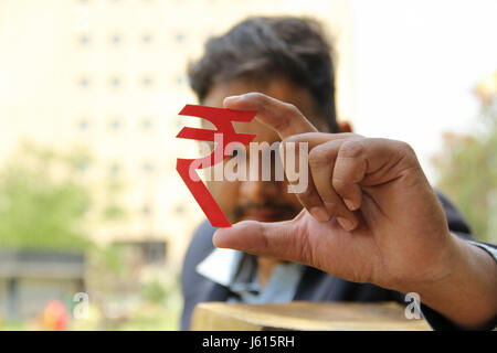 Giovani indiani business man guardando rupia indiana simbolo Foto Stock