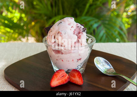 Piatto di gelato alla fragola con cioccolato fondente pezzi al di fuori nei tropichi Foto Stock