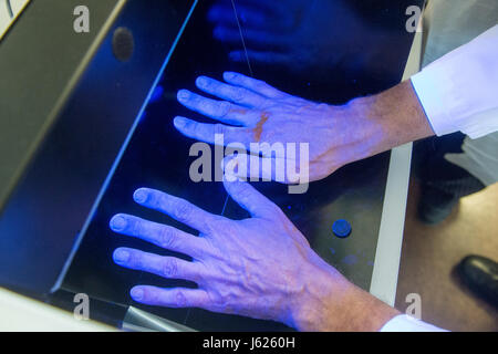 Regensburg, Germania. Decimo Apr, 2017. Wulf Schneider, professore di igiene ospedaliera, mantiene le sue mani - coperto di disinfettanti fluorescente - sotto la luce nera presso la clinica universitaria di Regensburg, Germania, 10 aprile 2017. Schneider è la Baviera il primo professore di igiene ospedaliera. Presso la clinica dell'Università di Regensburg egli fornisce una formazione avanzata per i medici e il personale medico, consigli cliniche in Baviera orientale e ricerche organismi multiresistenti. Foto: Armin Weigel/dpa/Alamy Live News Foto Stock