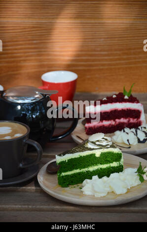 Bicchiere di frullato fragole e ghiaccio caffè con torta rossa del velluto sulla tavola di legno nella caffetteria. Foto Stock