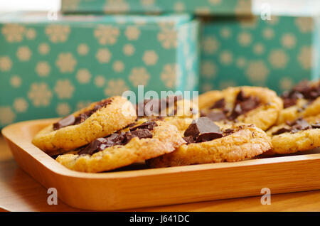 Deliziosi biscotti appena sfornati con il cioccolato su un vassoio in legno con uno sfondo sfocato Foto Stock