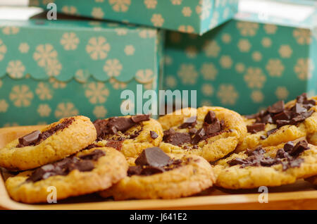 Close up di un deliziosi biscotti appena sfornati con il cioccolato su un vassoio in legno con uno sfondo sfocato Foto Stock