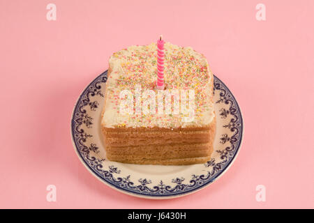 Un eccentrico ciliegina compleanno pane ricoperte con un pizzico su sfondo rosa Foto Stock