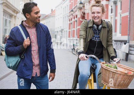 Giovane uomo e donna con la bicicletta su una strada di città Foto Stock