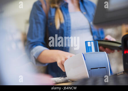 Shopper femmina usando un lettore di carte di credito in negozio Foto Stock