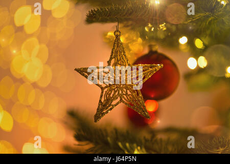 Vicino la stella d'oro ornamento pendente da albero di Natale ramo Foto Stock