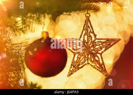 Close up ornamento rosso e oro stella appesa a partire dal ramo di albero di Natale Foto Stock