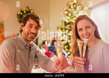 Ritratto sorridente giovane tostatura flauti champagne a Natale a tavola Foto Stock