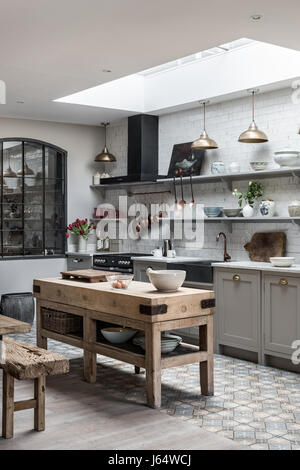 Aprire il piano cucina sophisticaed con ottone vintage illuminazione pendente e rustico in legno isola di Macellai Foto Stock