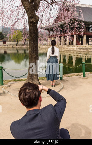 Un uomo di scattare le foto di una donna al Padiglione Gyeonghoeru nel Palazzo Gyongbokgung, Seoul, Corea del Sud Foto Stock