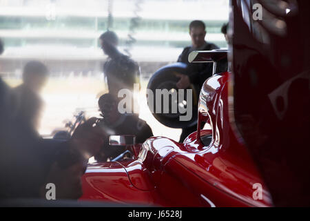 Pit Crew lavorando sulla gara di Formula Uno auto nel garage di riparazione Foto Stock