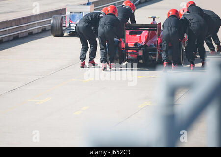 Pit Crew spingendo gara di Formula Uno auto al di fuori della pit lane Foto Stock