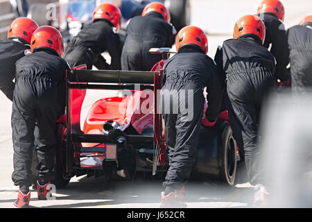 Pit Crew spingendo gara di Formula Uno auto al di fuori della pit lane Foto Stock