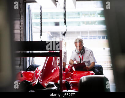 Manager con appunti esame di gara di Formula Uno auto nel garage di riparazione Foto Stock