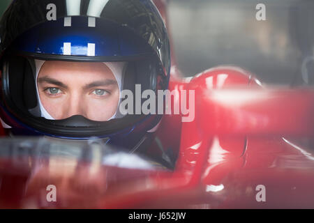 Close up focalizzata gara di Formula Uno pilota di auto nel casco che guarda lontano Foto Stock