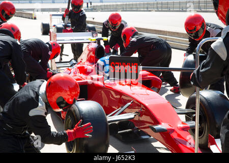 Pit Crew sostituiscono i pneumatici sulla gara di Formula Uno auto in pit lane Foto Stock