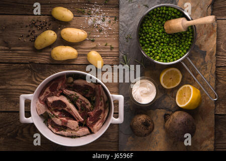 Costolette di agnello e patate, limone, piselli in un convogliatore Foto Stock