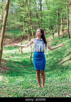 Giovane e bella ragazza sognante nel Parco di primavera diffondendo le mani e godersi il sole. Alberi verdi su sfondo. Foto Stock