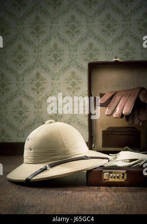 Explorer imballaggio con Apri cartella in pelle, midollo cappello, guanti in pelle su una superficie di legno. Foto Stock