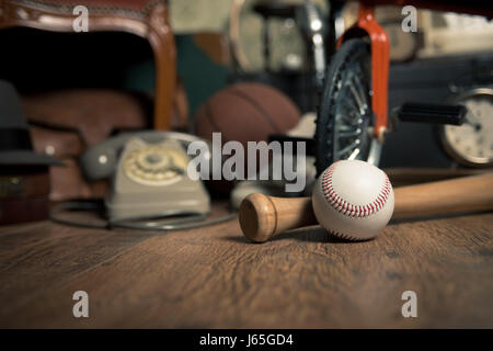 Gruppo di oggetti vintage attico sul pavimento di legno, compresi i vecchi giocattoli, telefono e articoli sportivi. Foto Stock