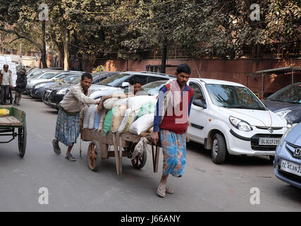 Lavoro duro indiani spingendo il carico pesante attraverso strade di Delhi, India nel febbraio, 13, 2016. Foto Stock