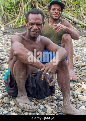 Mabul, Indonesia - 12 Gennaio 2015: predatori dell'oro dal villaggio di Mabul seduto su una riva di un fiume e godendo di una vista dei turisti in arrivo Foto Stock