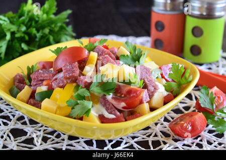 Insalata mista con salame salumi, formaggio, pomodoro e paprika con yogurt e salsa di aglio in un giallo vaso in ceramica. Cottura facile Foto Stock