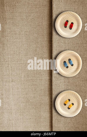 3 pulsante di legno con fili colorati su tela lo sfondo Foto Stock