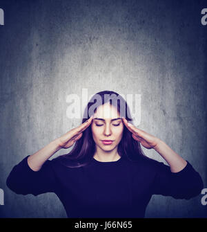 Sottolineato ansiosi donna con mal di testa isolata su grigio grunge sfondo a parete Foto Stock