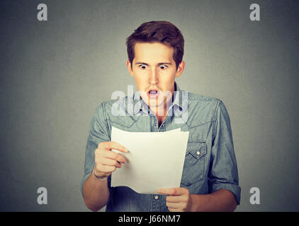 Scioccato uomo con alcuni documenti isolati su sfondo grigio Foto Stock